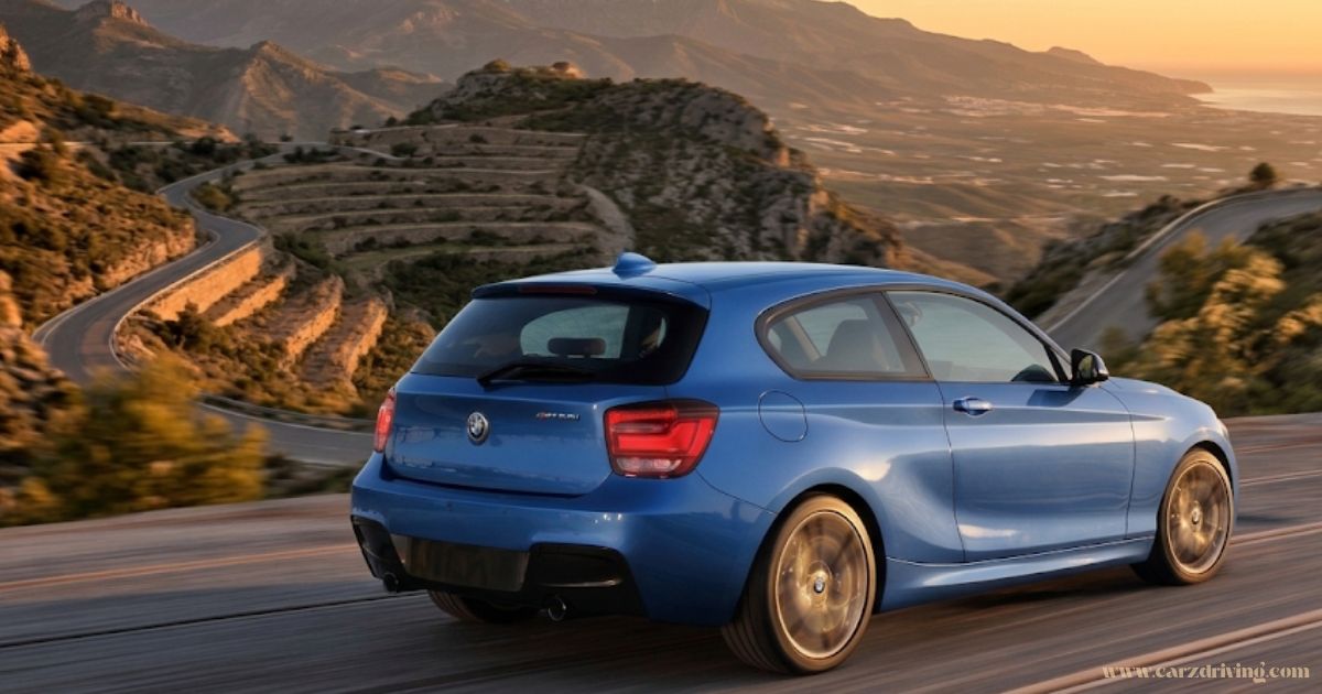 Blue BMW 135i hatchback driving along a winding mountain pass.