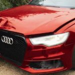 A damaged metallic red Audi station wagon shown from the front-left angle. The front bumper is cracked, and the hood is dented, illustrating a vehicle classified as Category N, signifying non-structural damage that is repairable.