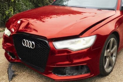 A damaged metallic red Audi station wagon shown from the front-left angle. The front bumper is cracked, and the hood is dented, illustrating a vehicle classified as Category N, signifying non-structural damage that is repairable.