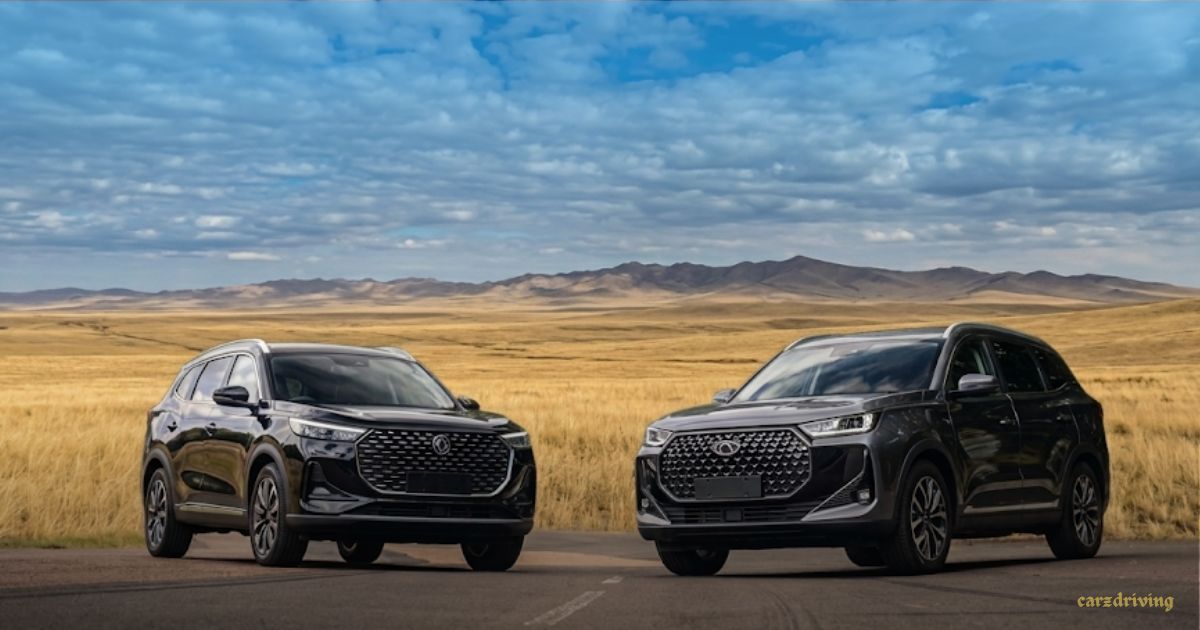 Two Chery Tiggo 9 SUVs, one black and one dark grey, parked side-by-side on an empty road with a scenic background of rolling hills and a cloudy blue sky.