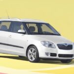 White Škoda Fabia station wagon with roof rails and alloy wheels, isolated on a yellow background.