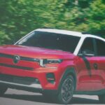 A front three-quarter view of a red Citroën compact SUV with a contrasting white roof and black pillars, captured in motion on a paved road. The background shows blurred green trees, indicating speed, and a "carzdriving" watermark is in the bottom right corner.