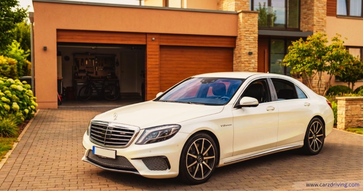 White Mercedes-AMG S65 luxury sedan with V12 Biturbo badging parked on a brick driveway in front of a modern house and open garage.