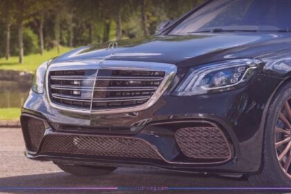 Close-up front view of a black Mercedes-AMG S65 luxury sedan featuring a chrome grille, distinctive LED headlights, and custom bronze multi-spoke alloy wheels parked outdoors.
