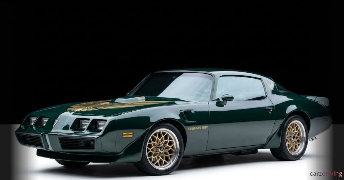 Dark green classic Pontiac Firebird Trans Am with gold hood decal and snowflake rims.