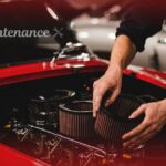 Mechanic replacing engine air filters during routine car maintenance on a classic red car