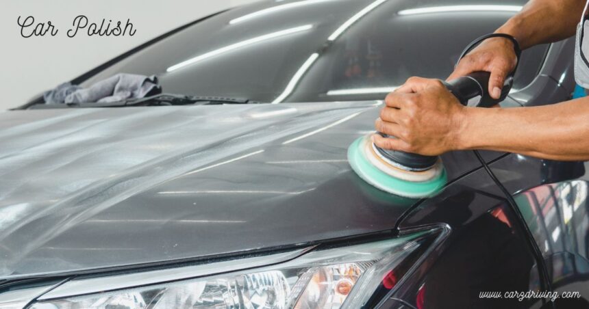 Person using a dual-action buffer machine to apply car polish onto a dark vehicle hood