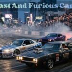 A classic black Fast and Furious car drifting alongside a silver and blue sports car on a racetrack packed with spectators.