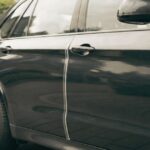 "Clear car door protector strip installed on a BMW X5 to prevent door dings and scratches in parking spaces."