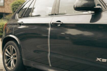 "Clear car door protector strip installed on a BMW X5 to prevent door dings and scratches in parking spaces."