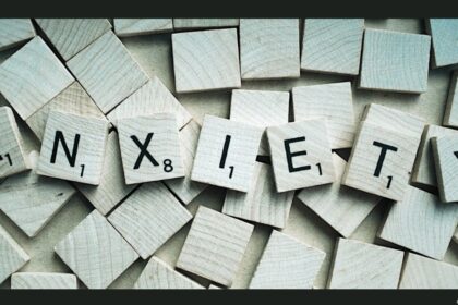Wooden letter tiles spelling out the word "anzieti" arranged across a background scattered with blank wooden tiles.