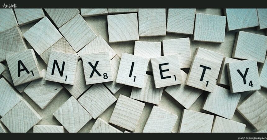 Wooden letter tiles spelling out the word "anzieti" arranged across a background scattered with blank wooden tiles.