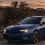 Blue Opel Astra Sports Tourer estate car driving on a scenic road at sunset.