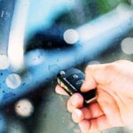 Hand pressing a button on a car alarm remote key fob with "Car Alarm" overlay text