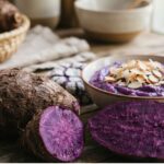 Fresh whole and sliced purple ube yams next to a bowl of ube dessert to explain what is ube