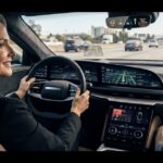 Displaying car technology impact on driving,Driver smiling behind the steering wheel of a modern car featuring a digital dashboard, heads-up display, and advanced navigation technology while driving on a highway.