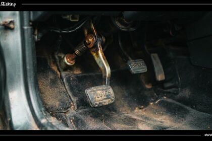 Close-up view of a worn car clutch pedal mechanism inside a vehicle footwell showing potential mechanical wear causing a clutch pedal sticking