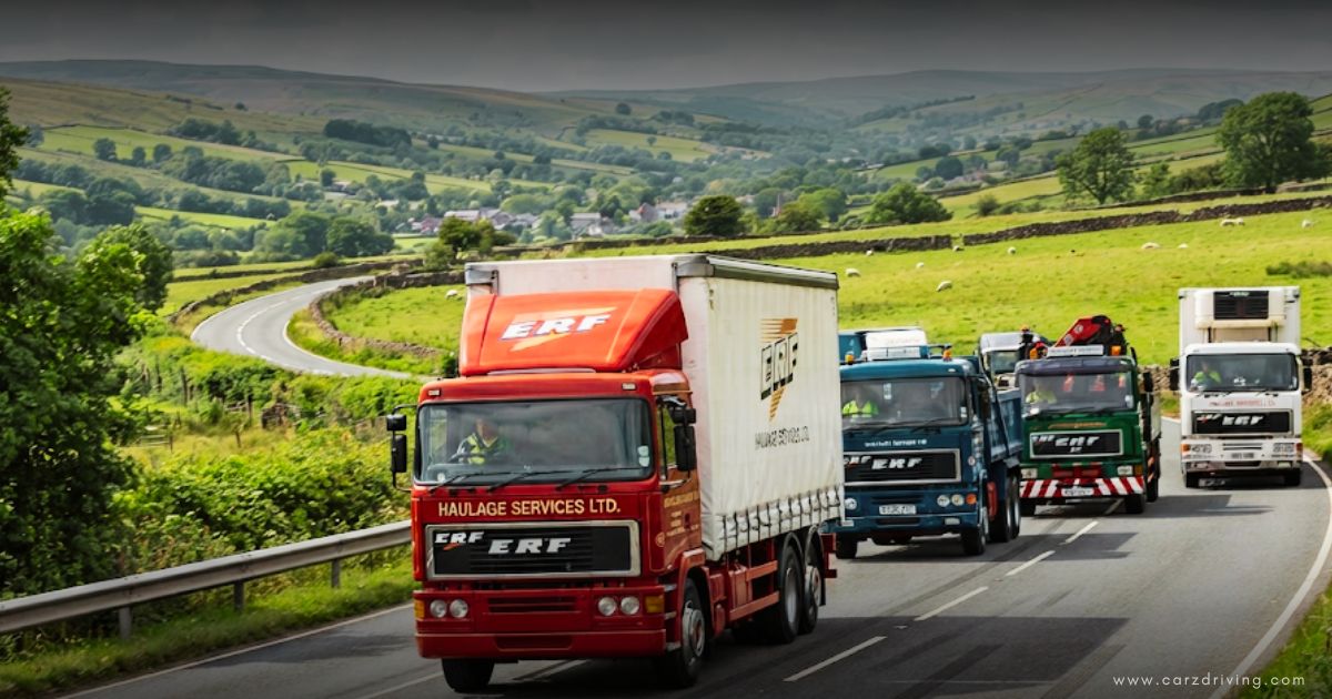 A fleet of classic ERF trucks on a rural road featuring a prominent red haulage truck in the lead.