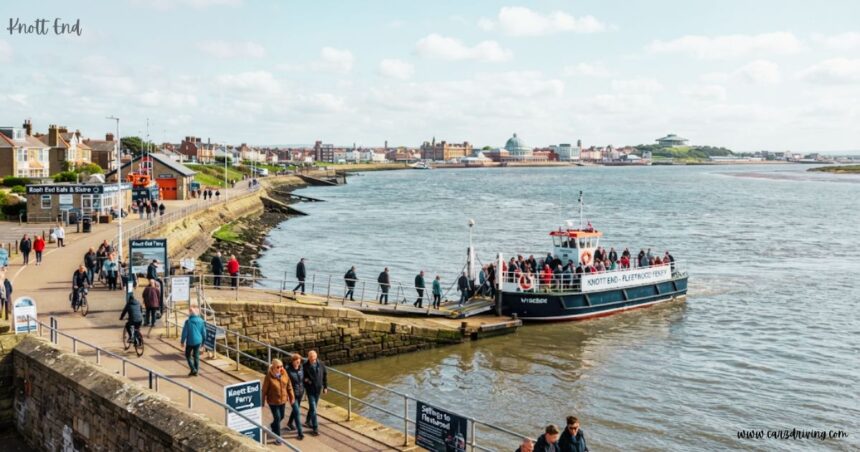The Knott End–Fleetwood Ferry, filled with passengers, docked at a stone slipway along a coastal promenade.