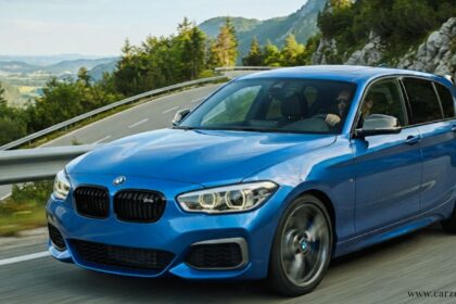 Blue BMW M140i performance hatchback driving along a scenic mountain road