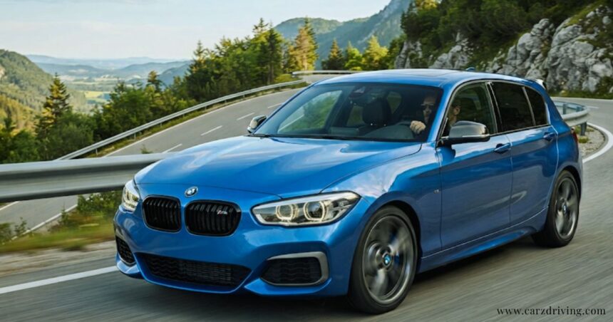 Blue BMW M140i performance hatchback driving along a scenic mountain road