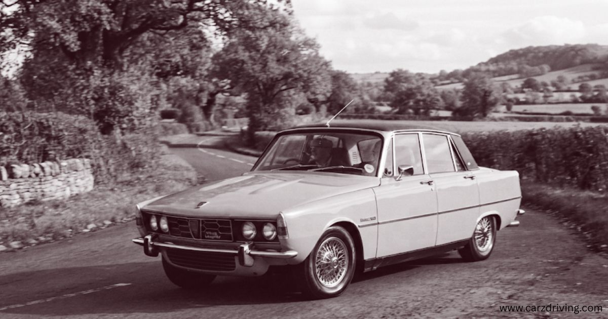 A classic Rover P6 sedan driving along a winding country road
