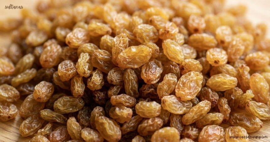 Close-up of a pile of golden-brown sultanas raisins on a wooden surface.