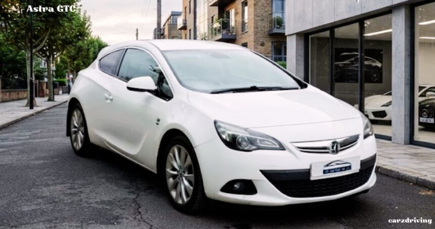 A white Vauxhall Astra GTC parked on a city street next to a modern building.