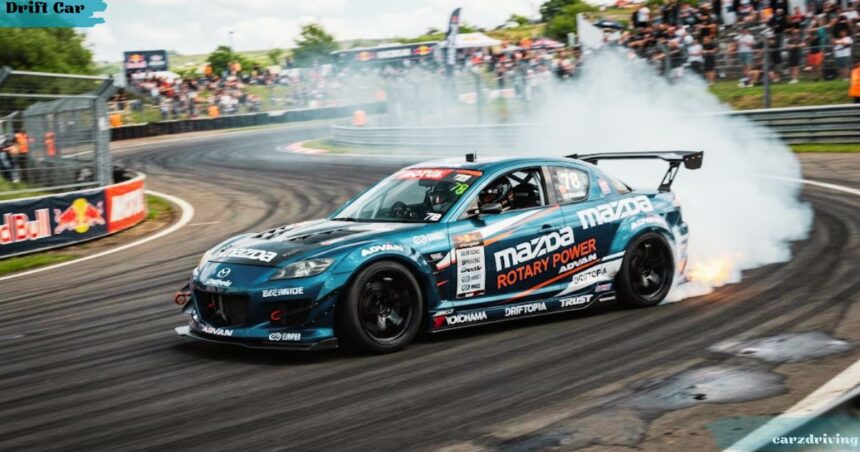 Mazda RX-8 drift car sliding around a track corner, generating thick white tire smoke and flames from the exhaust while spectators watch from the background.