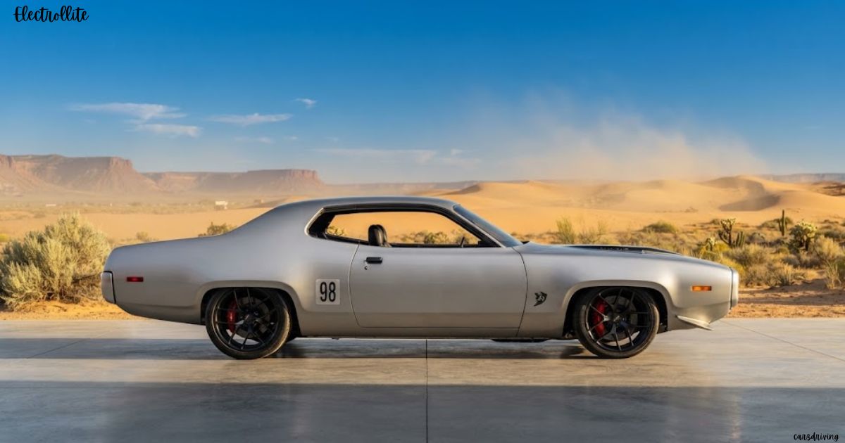 A profile view of a vintage silver muscle car parked on a concrete surface against a desert landscape with sand dunes and mesas under a blue sky, with the text "Electrollite" in the top left corner and the number "98" on its side panel.