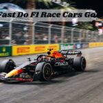 An F1 race car accelerating at high speed past barriers during a night grand prix event. at the mid lay how fast do f1 race cars go