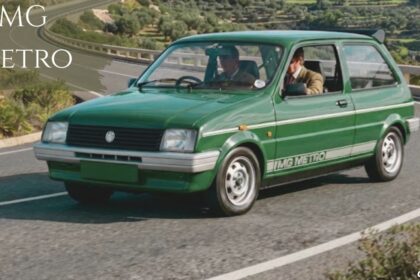 A vintage green MG Metro hatchback driving along a winding coastal road, featuring white side striping with "MG METRO" text, a rear spoiler, and overlay text reading "MG METRO" in the top-left corner.