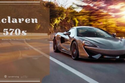 A grey McLaren 570S sports car driving along a scenic mountain road at sunset.