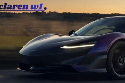 Front three-quarter dynamic shot of a deep purple McLaren W1 super sports car driving fast on a country road at dusk with headlamps illuminated.