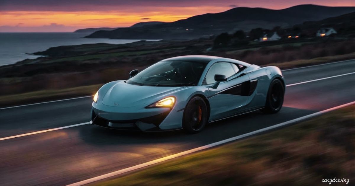 Light blue McLaren 570S sports car driving along a coastal road at sunset.