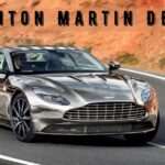 Silver Aston Martin DB11 sports car driving along a winding mountain road